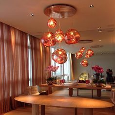 a dining room table with many lights hanging from it's ceiling and chairs around it