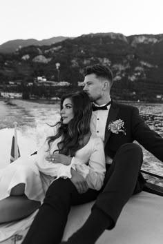 a man and woman sitting on the back of a boat in black and white photo