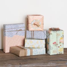 four wrapped presents sitting on top of a wooden table next to a clock and wall