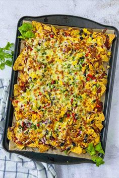 Loaded nachos on a sheet pan placed on white surface.