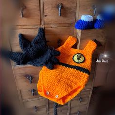 an orange and black crocheted hat sitting on top of a wooden dresser next to other items