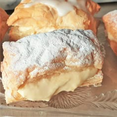 several pastries sitting on top of a glass plate covered in powdered sugar and icing