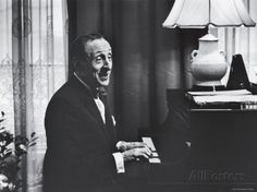 a man in a suit and tie sitting at a piano with his mouth wide open