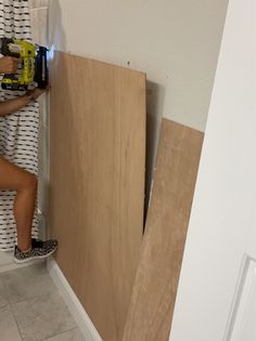 a woman is using a drill to install the door frame in her bathroom, while she stands on one leg