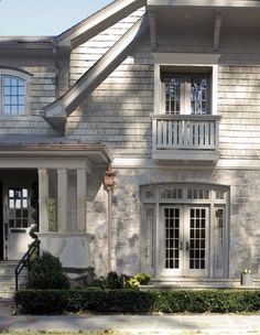 a large gray brick house with two story windows and balconies on the second floor