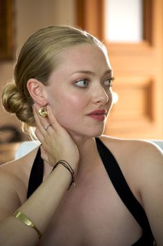 a woman with her hand on her chin looking at the camera while wearing a black halter top