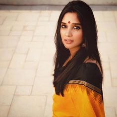 a woman with long black hair wearing a yellow top