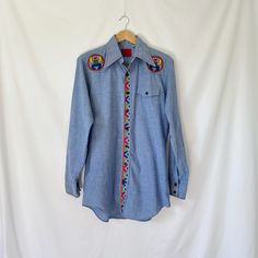 Vintage 1970's Embroidered Denim Chambray Shirt Brand ~ King Roads Shop by Sears Original Tags - Yes (tagged as medium) Measurements taken flat ~  PTP 22 in. Neck 15-15.5 in.  Shoulder seam to seam 17 in.  Length 32 in. Fabric - Cotton/Poly Condition - Good  Item has been pre-washed or cleaned - smoke free home. Measurements taken flat. This is a vintage item - please keep this in mind before purchase. There may be small wear due to age but I will be sure to mention any larger issues with garmen Blue Vintage Western Style Tops, Vintage Blue Tops For Rodeo, Retro Embroidered Cotton Shirt, Vintage Embroidered Tops For Rodeo, Retro Embroidered Blue Top, Retro Blue Embroidered Top, Pink Shawl, Vintage Shawls, Western Denim Shirt