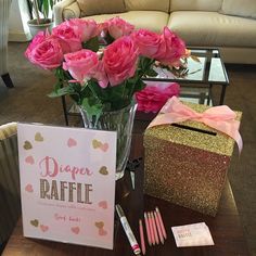 pink roses are in a vase next to a card and some pens on a table