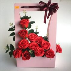 there is a pink box with red roses in it