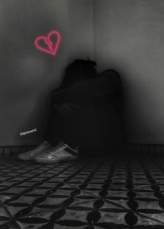 a person sitting on the floor in front of a wall with a heart drawn on it