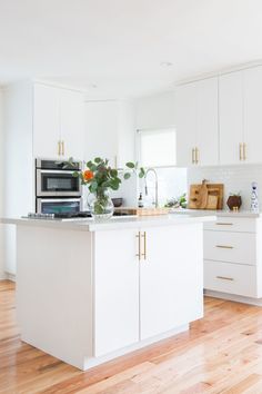 a kitchen with white cabinets and an island that has flowers in it on the counter