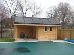 a small wooden shed with a blue tarp on the roof and a chair in the back yard