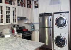 a kitchen with white cabinets and marble counter tops