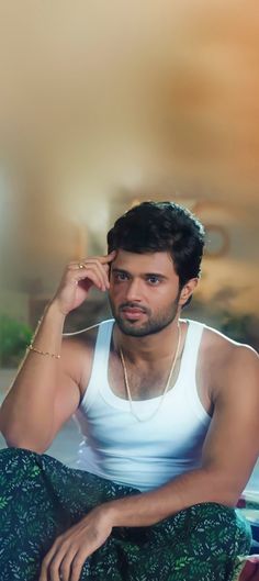 a man in white tank top and green pants sitting on the floor with headphones