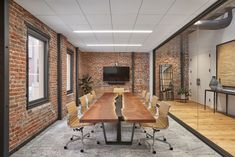 an empty conference room with brick walls and wooden tables in the center, along with white chairs