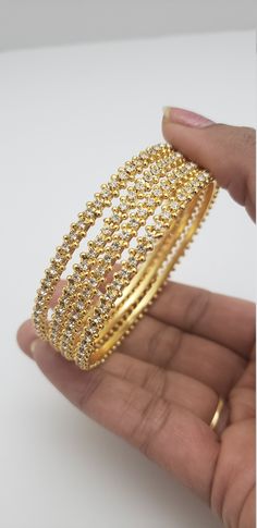 "* Handcrafted Gold Plated 4 Bangle Set. Sold as a set. * Bangles with high quality CZ stones. * High Quality 22K Gold Plated. Bangles Sizes : 2.4 inches= ( 2.25\" diameter of the inner circle) ; 2.6 inches = ( 2.39\" diameter of the inner circle); 2.8 inches = (2.54\" diameter of the inner circle) The gorgeous gold-plated bangles set best exemplifies the careful craftsmanship done on it -- specially picked for you by Nemali Jewelry. It has a special tone of elegance attached to it. The intricat Gold Bracelets With Stone Work For Anniversary, Gold Bracelets With Stone Setting For Celebration, Gold Bracelet With Stone Setting For Celebration, Gold Bangle With Cubic Zirconia Stone Setting, Gold Bracelet With American Diamond, Round Shape, Gold Bangle With Cubic Zirconia Stone Work, Dazzling Gold Bridal Sets For Celebration, Gold Bangle With Stone Setting For Celebration, Gold Wedding Bracelets With Stone Setting