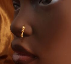 a close up of a woman's nose with a gold nose ring on it