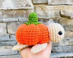 a hand holding a small crocheted turtle with a carrot on it's back