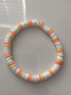 an orange, white and yellow beaded bracelet with silver clasp on a white surface