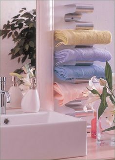 a bathroom sink with towels hanging on the wall and a vase full of flowers next to it