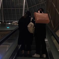 two people on an escalator with shopping bags over their heads and one holding a bag