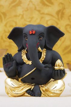 an elephant statue sitting on top of a gold plated table next to a wall