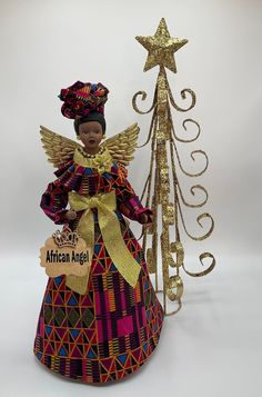 "Celebrate pride and beauty with our unique AFRICAN ANGEL Tree Topper and give your loved ones the gift of representation that reflects images of you and your family. Our Beautiful Angel Tree Topper add the perfect final touch to your Christmas, Kwanzaa and Home Decorating. (Please see listings for other available styles, as seen in the collection photo: Purple, Baby Blue, Pink and Blue Metallic Gold colors). OPTIONAL: Clear Display Case Let me tell you more about this AFRICAN ANGEL (Dressed in African Angel, Photo Purple, Porcelain Angel, Christmas Tree Angel, Metallic Gold Color, Angel Tree Topper, Angel Dress, Angel Tree, Kwanzaa