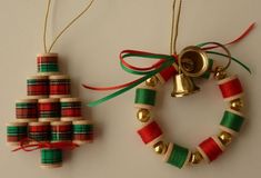 two christmas ornaments hanging from strings on a white surface with red, green and gold ribbons