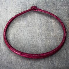 a red leather cord bracelet sitting on top of a table