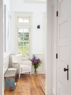 a white chair sitting in a room next to a wooden floor with a window above it