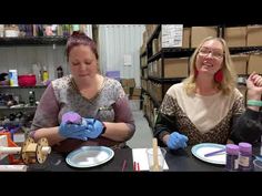 two women are sitting at a table with craft supplies