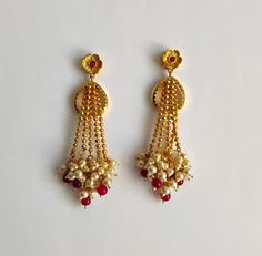 Vintage Handmade in Bangladesh gold tone cream faux pearl and red glass bead cluster tassel fringe statement earrings. Flower post with open work on the sides of the flowers. Gold tone ball chains through a sawtooth teardrop shape drop. Excellent condition with shiny polish and free of wear with light tarnish on the post. The earrings came with the bottom part of the original box.  Size: 3.5" x 1.25"  Thank you for visiting our shop! Please refer to photos as part of the description. Please Chec Festive Gold Beaded Pearl Earrings, Festive Gold Beaded Earrings With Pearl Drop, Red Pearl Drop Earrings For Festive Occasions, Red Dangle Pearl Earrings For Festive Occasions, Festive Red Pearl Drop Earrings, Traditional Red Dangle Pearl Earrings, Red Pearl Earrings For Celebration, Red Pearl Drop Earrings For Celebration, Red Latkans Dangle Bridal Earrings