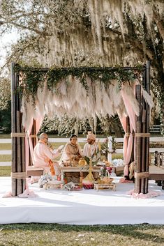 a group of people sitting at a table in front of a gazebo with feathers on it