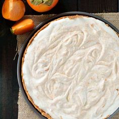 a pie sitting on top of a wooden table next to an orange and some other fruit