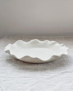 a white bowl sitting on top of a table next to a wall in the background