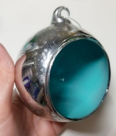 a close up of a person's hand holding a blue ball ornament