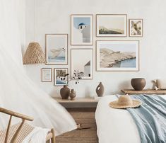 a bedroom with white walls and pictures on the wall above the bed, along with wicker furniture