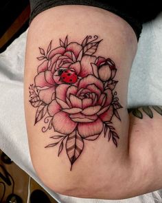 a ladybug sits on top of a rose tattoo