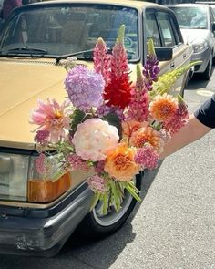 a bouquet of flowers sitting on the hood of a car in front of parked cars