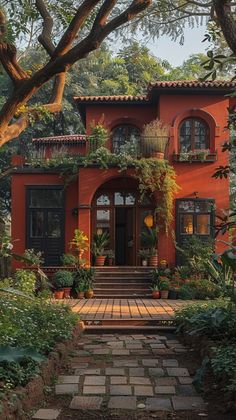 a red house with lots of plants and trees on the front door, surrounded by greenery