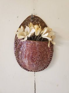 there is a vase with flowers in it hanging on the wall