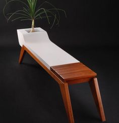 a wooden bench with a potted plant sitting on it's back end, in front of a black background