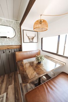 a table and bench in a room with wood flooring next to a wall mounted deer head