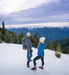 two people standing on top of a snow covered slope