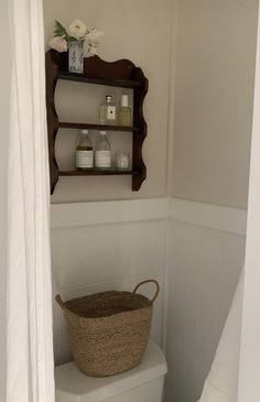 a white toilet sitting in a bathroom next to a wooden shelf