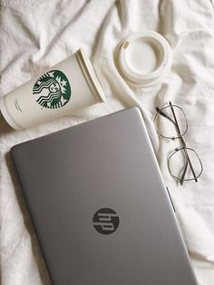 an open laptop computer sitting on top of a bed next to a cup of coffee