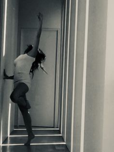 a woman standing on one leg in the middle of a hallway