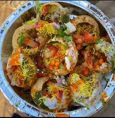 a silver bowl filled with lots of food on top of a metal pan covered in condiments