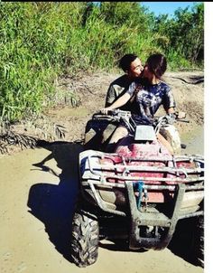 two people riding an atv in the mud